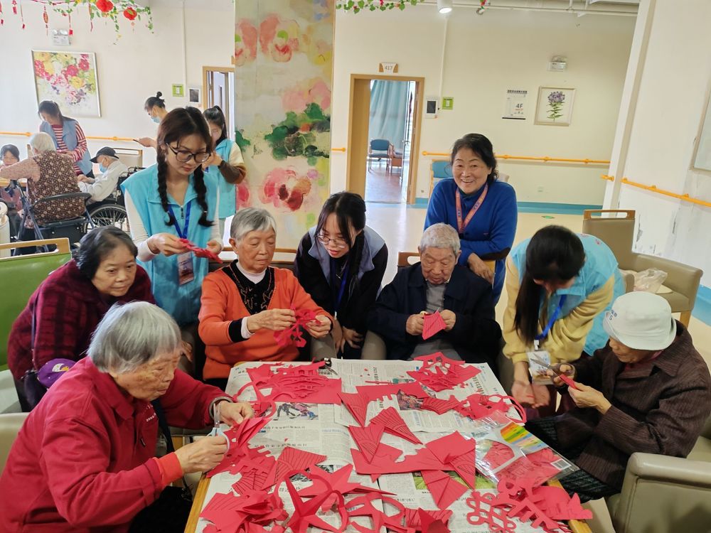 同学们与老人一起剪纸